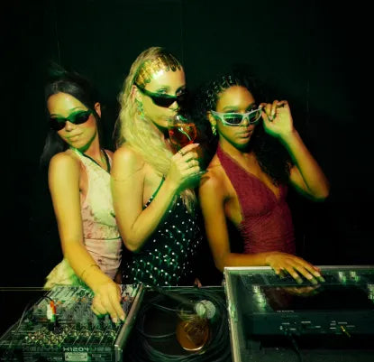 3 raparigas num festival de verão, com óculos de sol e mesa de DJ