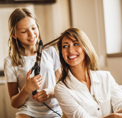 Filha enrolando o cabelo da mãe e divertindo-se em casa